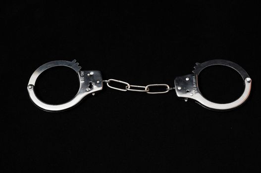 One Pair of Handcuffs on a Black Background