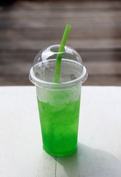 Soft drink in plastic cup with green straw