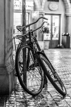 Two old bikes tied to a pole on the side of the street