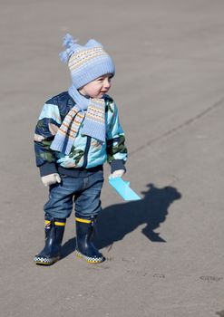 Little boy goes on a pool in rubber boots