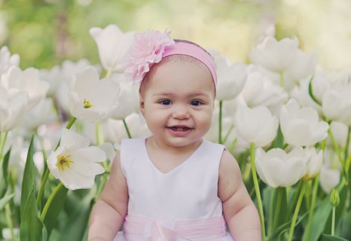 Little girl in an elegant dress to stand near blossoming tulips