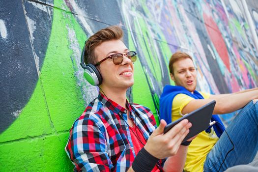 Portrait of happy teens boy near painted wall listening to music