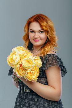 Attractive red-haired girl holding a bouquet of yellow flowers