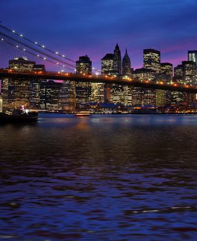  Brooklyn Bridge, East River and Manhattan at sunset with lights and reflections. New York