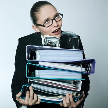 studio shot portrait of one caucasian young businesswoman  wearing heavy files and folders