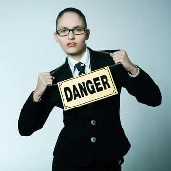 studio shot portrait of one caucasian young dangerous business woman woman  wearing a danger sign