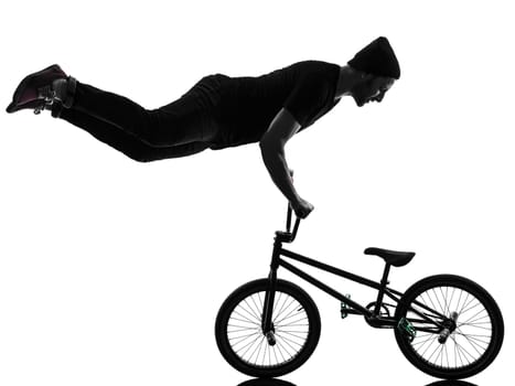 one caucasian man exercising bmx acrobatic figure in silhouette studio isolated on white background