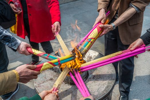 Shanghai, China - April 7, 2013: close up picture on people hands burning incense for praying  at the city of Shanghai in China on april 7th, 2013