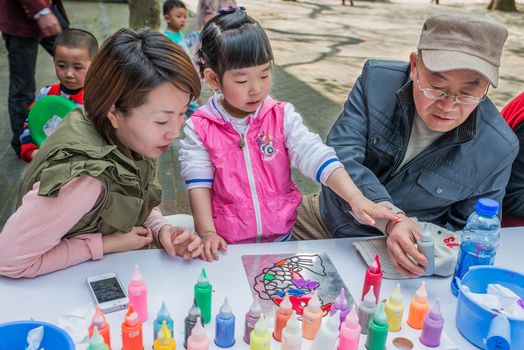 Shanghai, China - April 7, 2013: three generation family sketching leisure in fuxing park at the city of Shanghai in China on april 7th, 2013