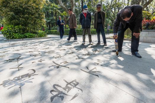 Shanghai, China - April 7, 2013: man writing  chinese calligraphy with water  in fuxing park at the city of Shanghai in China on april 7th, 2013