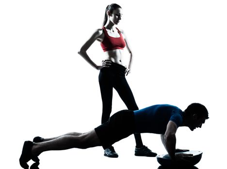 personal trainer man coach and woman exercising abdominals push ups on bosu silhouette  studio isolated on white background