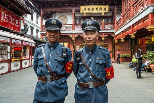 Shanghai, China - April 7, 2013: two tourist policemen posing and smiling in Fang Bang Zhong Lu old city  at the city of Shanghai in China on april 7th, 2013