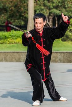 Shanghai, China - April 7, 2013: one man exercising tai chi with traditional costume in gucheng park in the city of Shanghai in China on april 7th, 2013