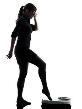 one anxious  woman standing on weight scale silhouette studio isolated on white background