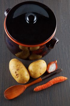 Potatoes, carrot and onion near a big old pot