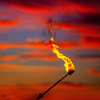 Fire torch at sunset sky with red clouds background