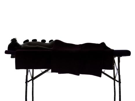 one woman lying on a massage table in silhouette studio on white background
