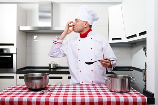 Male chef at kitchen tasting the dish