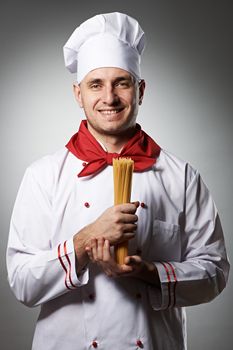 Male chef holding pasta against grey background