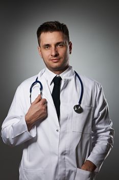 Medical doctor with stethoscope portrait against grey background 