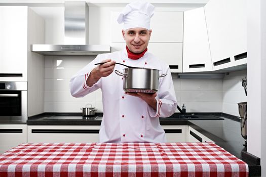 Male chef at kitchen tasting the dish