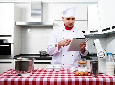 Male chef at kitchen with tablet pc getting ready to cook