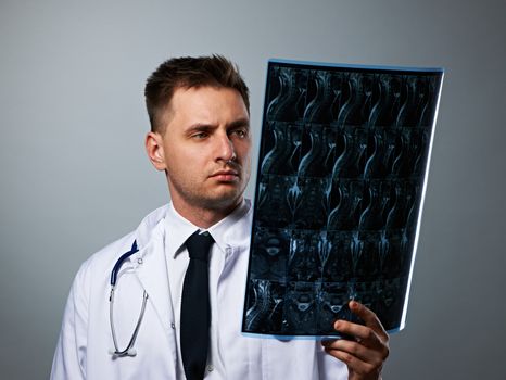 Medical doctor with MRI spinal scan portrait against grey background 