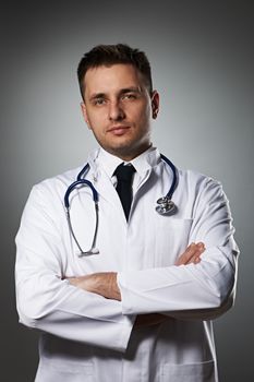 Medical doctor with stethoscope portrait against grey background 