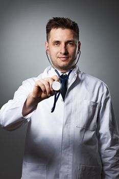 Medical doctor with stethoscope portrait against grey background 