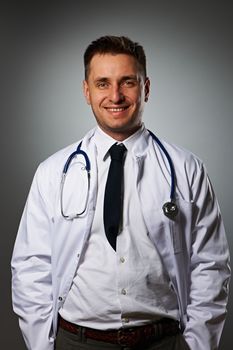 Medical doctor with stethoscope portrait against grey background 