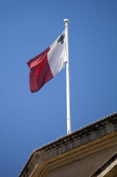 Waving Flag of Republic of Malta against blue sky