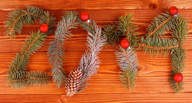 Arrangement of Spruce Branch, Fir Cone and Red Baubles as New Year 2014 closeup on Wooden background