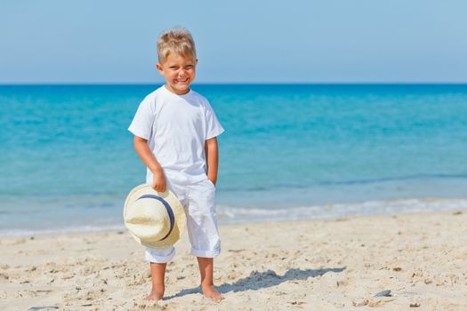 Smiling cute boy with a sun hat at the tropical beach.