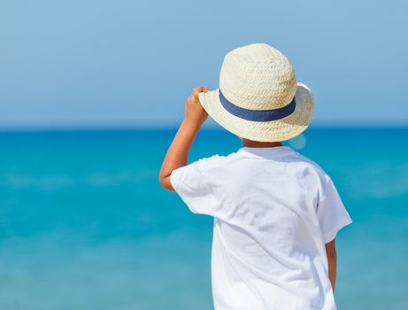 Smiling cute boy with a sun hat at the tropical beach.
