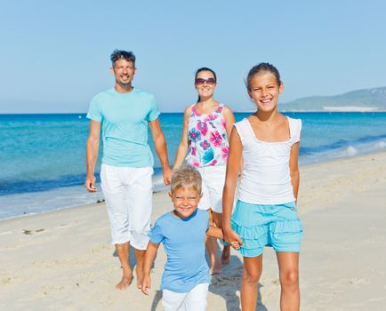 Family of four having fun on tropical beach