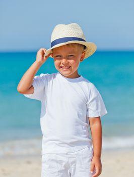 Smiling cute boy in a sun hat at the tropical beach. Vertical view