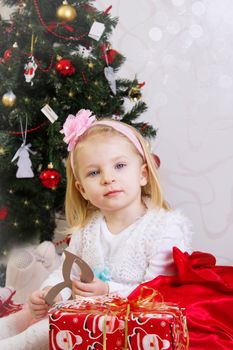 Adorable girl in pink under Christmas tree with gifts