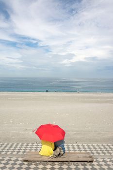 Couple sitting on beach under red umbrella. Shot at famous attraction, Qixingtan Beach in Hualien, Taiwan, Asia.