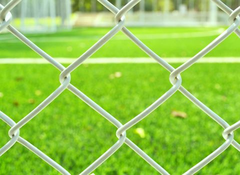 Metal net at soccer field with green grass.