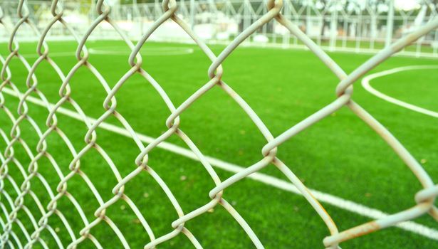 Metal net at soccer field with green grass.