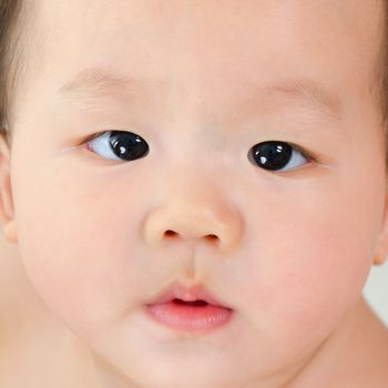 Close up face of Asian baby boy with curious look