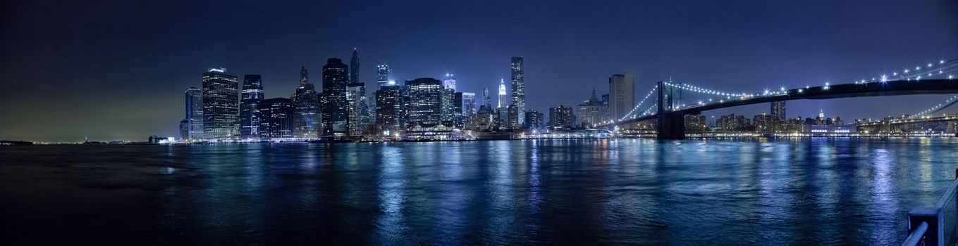 The New York City skyline in the night w Brooklyn Bridge Hi-Res
