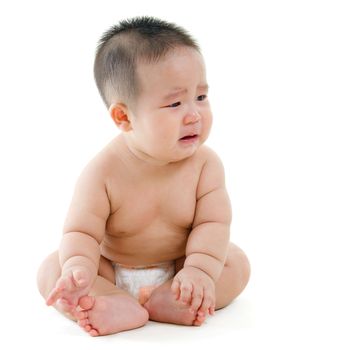 Full body sad Asian baby boy crying, sitting isolated on white background