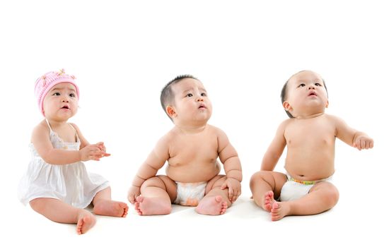 Group of Asian babies looking up, sitting isolated on white background