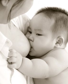 Mother and baby. Close up Asian mother breastfeeding baby boy in sepia tone.