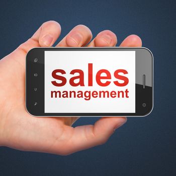 Marketing concept: hand holding smartphone with word Sales Management on display. Mobile smart phone in hand on Blue background, 3d render
