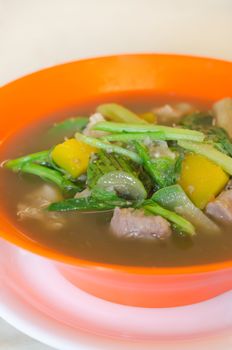 close up savoury thick soup made from pork , spices and mix vegetable in orange  bowl 