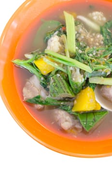 top view savoury thick soup made from pork , spices and mix vegetable in orange  bowl over white background