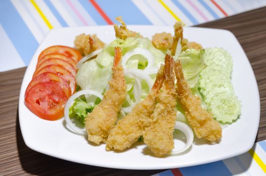 deep fried shrimp and  fresh vegetable salad on white dish