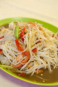 spicy papaya salad with rice noodles and mix vegetable on green dish